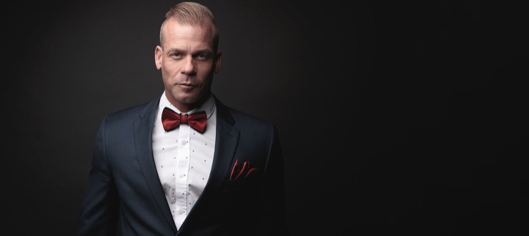 Studio portrait of a man in a navy suit and bow tie against a dark backdrop, ATX Headshots