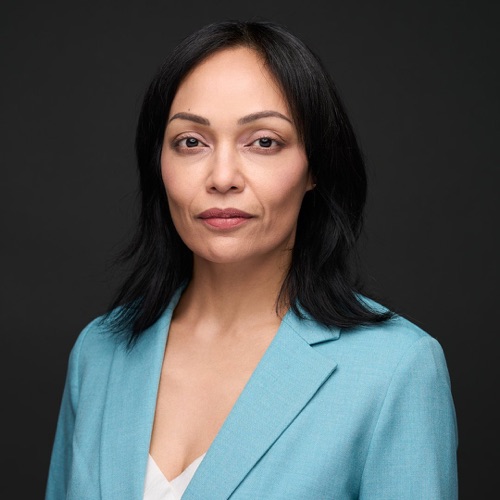 Headshot of a woman with dark hair in a teal blazer against a dark backdrop, ATX Headshots