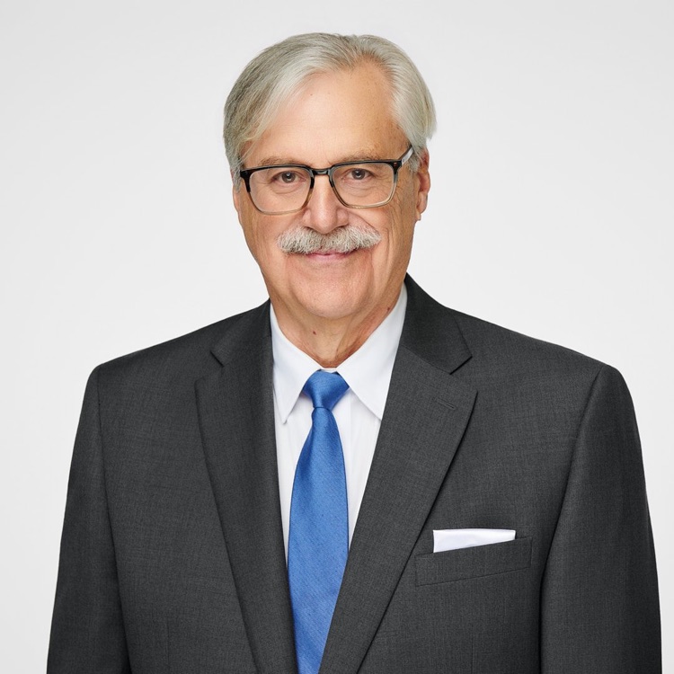 Headshot of a smiling older man in glasses, a grey suit and blue tie, ATX Headshots