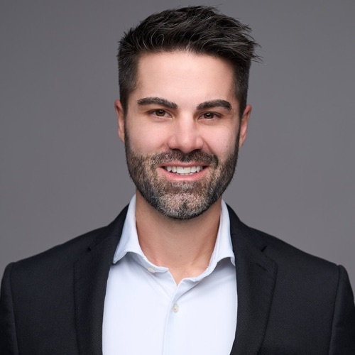 Headshot of a smiling bearded man in a dark blazer and white open-collar shirt, ATX Headshots