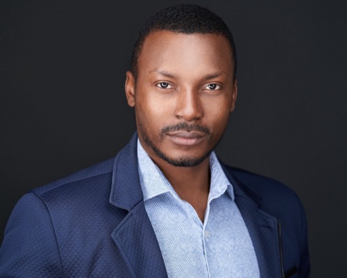Headshot of a man in a navy blazer and light blue shirt against a dark backdrop, ATX Headshots