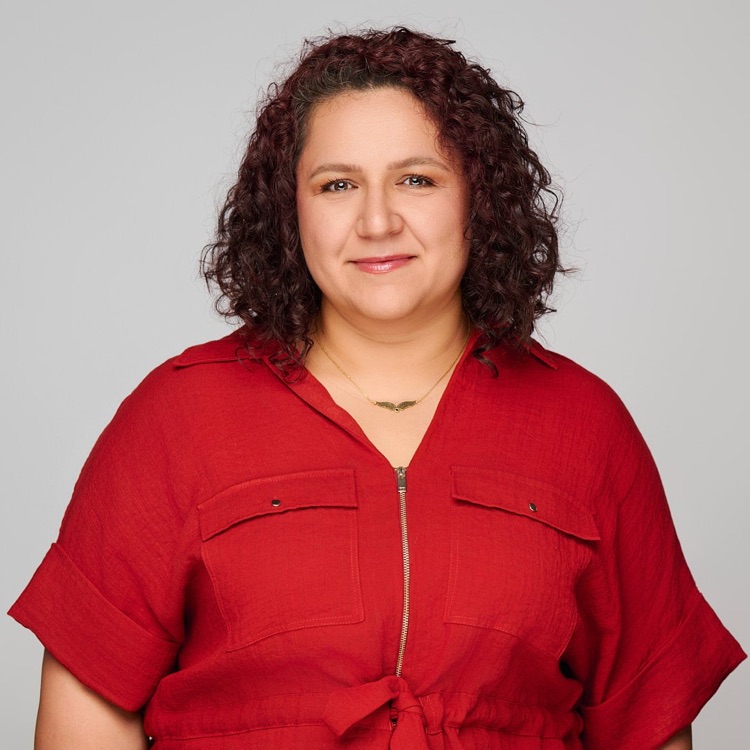 Headshot of a woman in a solid red short-sleeved top, light grey background