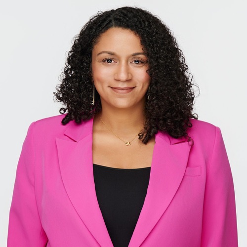 Headshot of a smiling woman with curly hair in a pink blazer, ATX Headshots