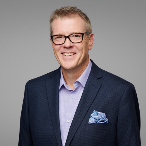 Headshot of a smiling man in glasses, a navy blazer and pocket square, ATX Headshots