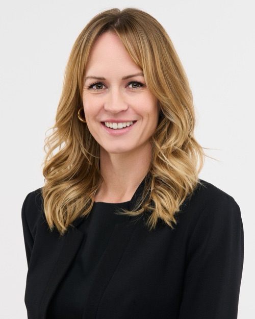 Headshot of a smiling woman with wavy blonde hair in a black top, ATX Headshots