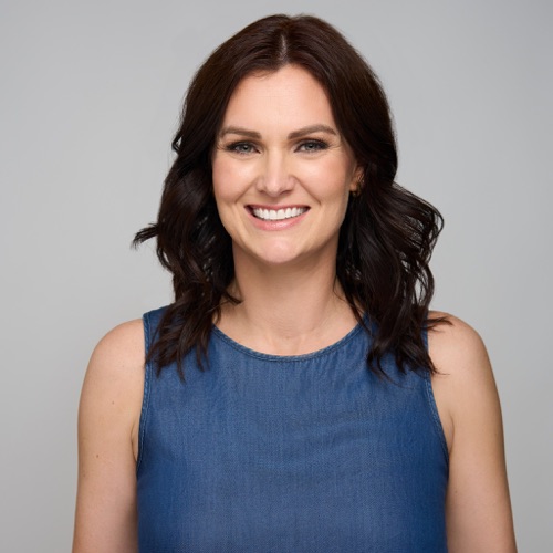 Headshot of a smiling woman with dark wavy hair in a blue sleeveless top, ATX Headshots