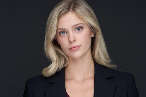 Headshot of a woman with long blonde hair in a black blazer against a dark backdrop, ATX Headshots