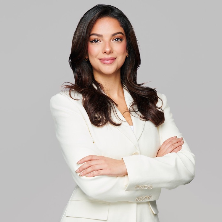 Portrait of a woman in a white jacket with arms folded, light background