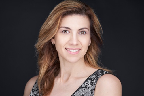 Headshot of a smiling woman with long auburn hair against a dark backdrop, ATX Headshots