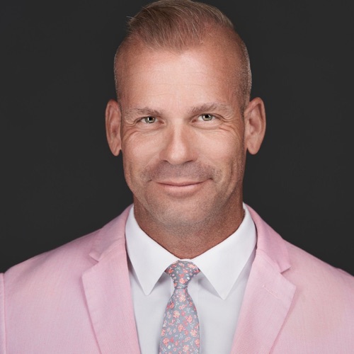 Headshot of a smiling man in a pink blazer and floral tie, by Ryan Dunbar at ATX Headshots
