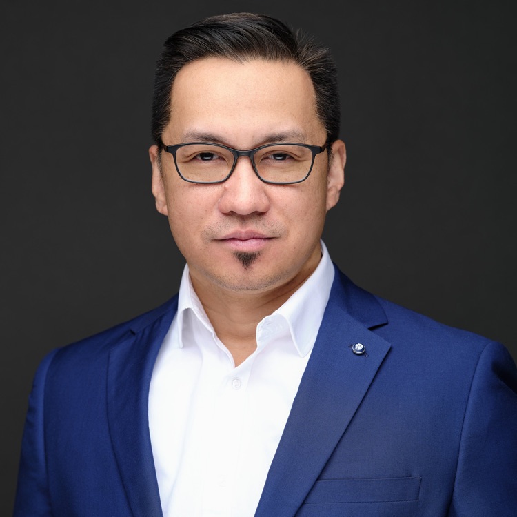 Headshot of a man in glasses and a navy blazer against a dark backdrop, ATX Headshots
