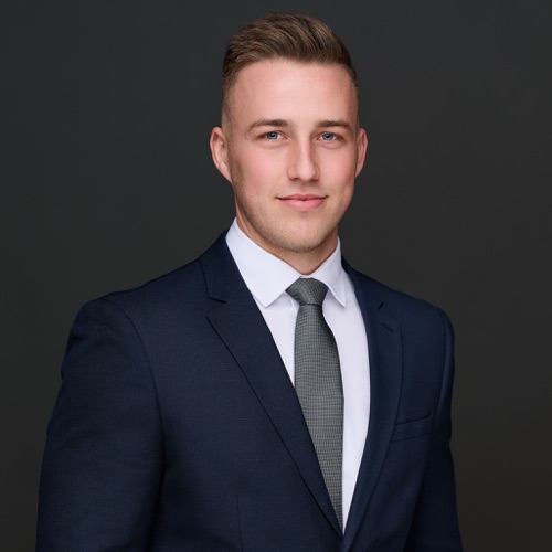 Corporate headshot of a young man in a navy suit and grey tie, ATX Headshots