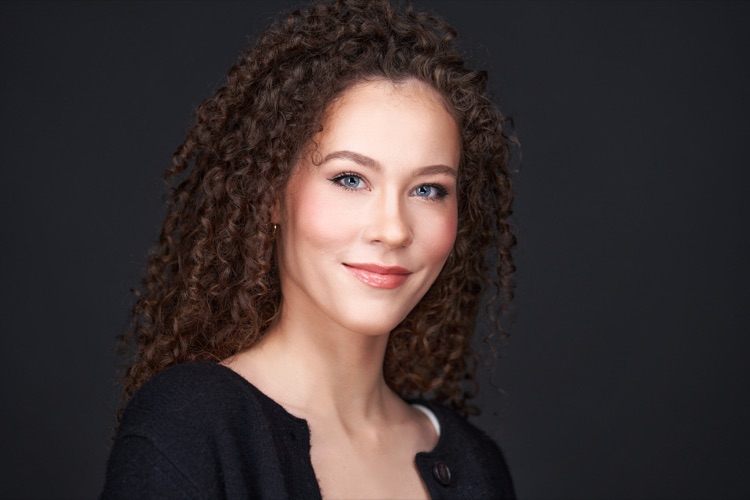 Studio headshot of a smiling woman with curly hair in a black top, ATX Headshots Cedar Park studio