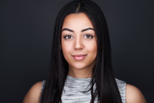 Headshot of a woman with long dark hair against a dark backdrop, ATX Headshots