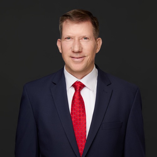 Executive headshot of a man in a navy suit and red tie against a dark backdrop, ATX Headshots