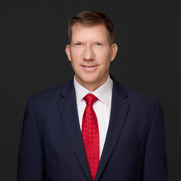 Executive headshot of a man in a navy suit and red tie against a dark backdrop, ATX Headshots