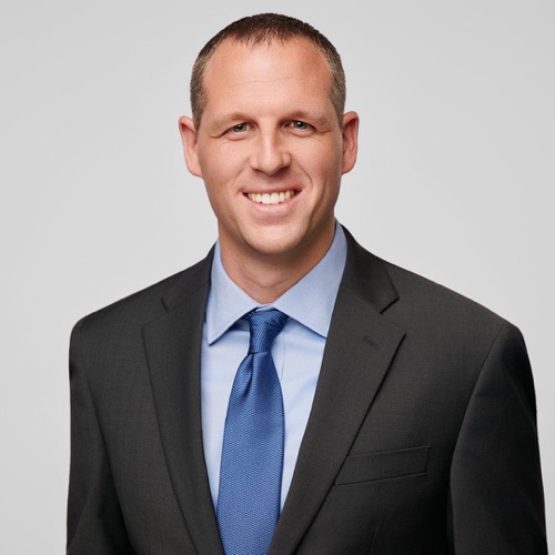 Headshot of a smiling man in a grey suit and blue tie, ATX Headshots