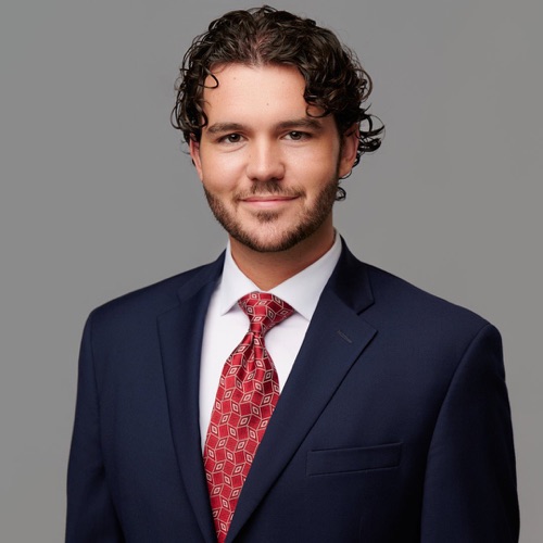 Headshot of a man with curly hair in a navy suit and red tie, ATX Headshots